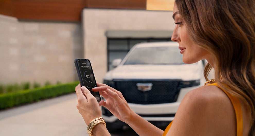 lady checking her mobile with a Cadillac vehicle background | Courtesy Cadillac Broussard in Broussard LA